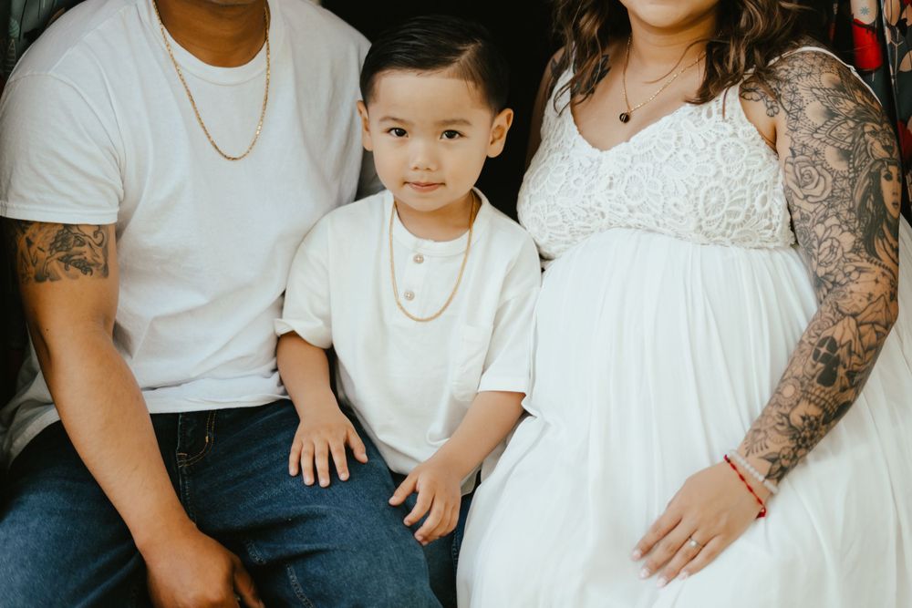 Family wearing coordinated white outfits poses together for a casual portrait session outdoors.