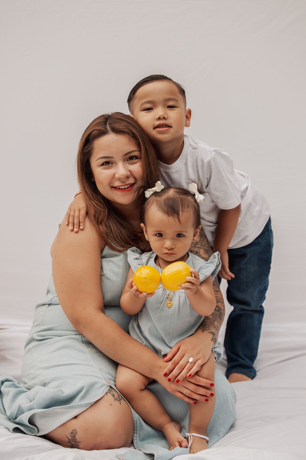 A sweet family photo session on white bedding shows tender moments of embrace and connection in matching blue outfits.