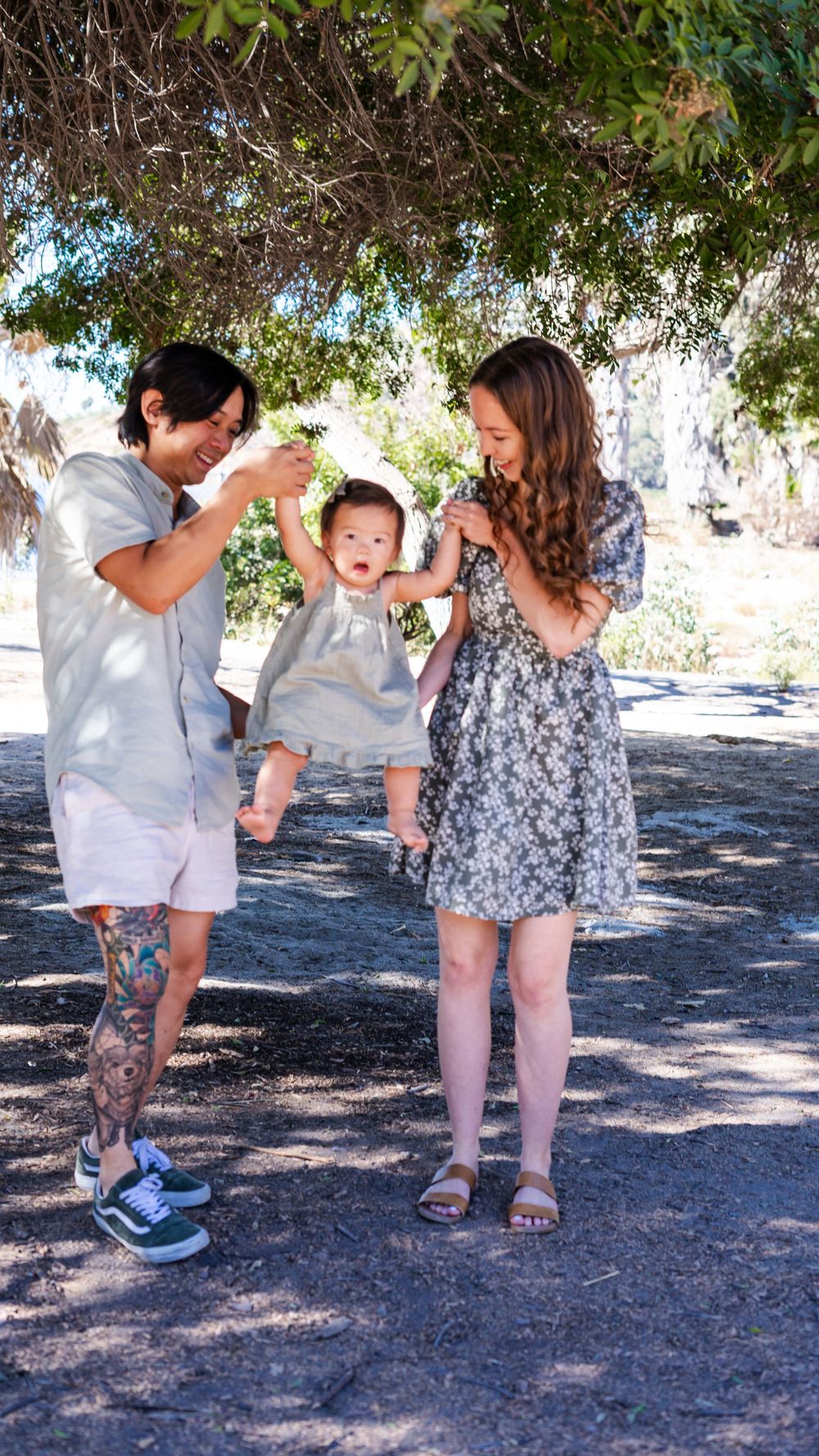 a photo of mother, father and baby under a tree
