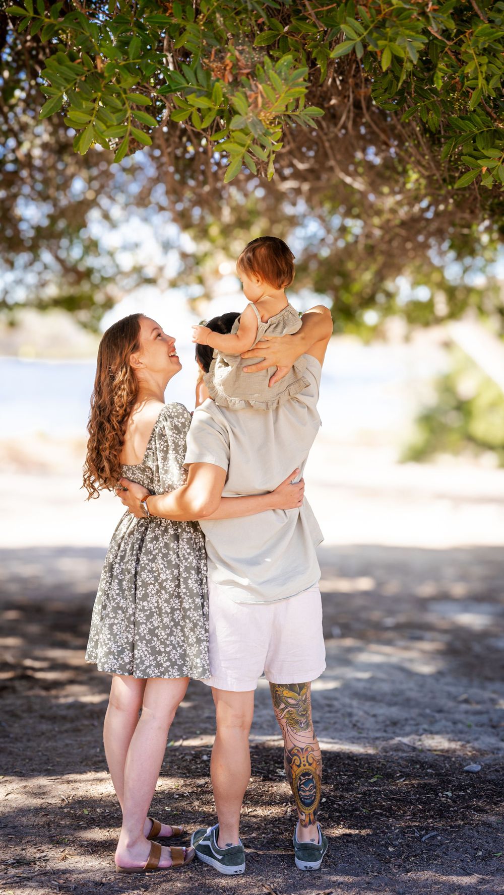 a photo of mother, father and baby under a tree