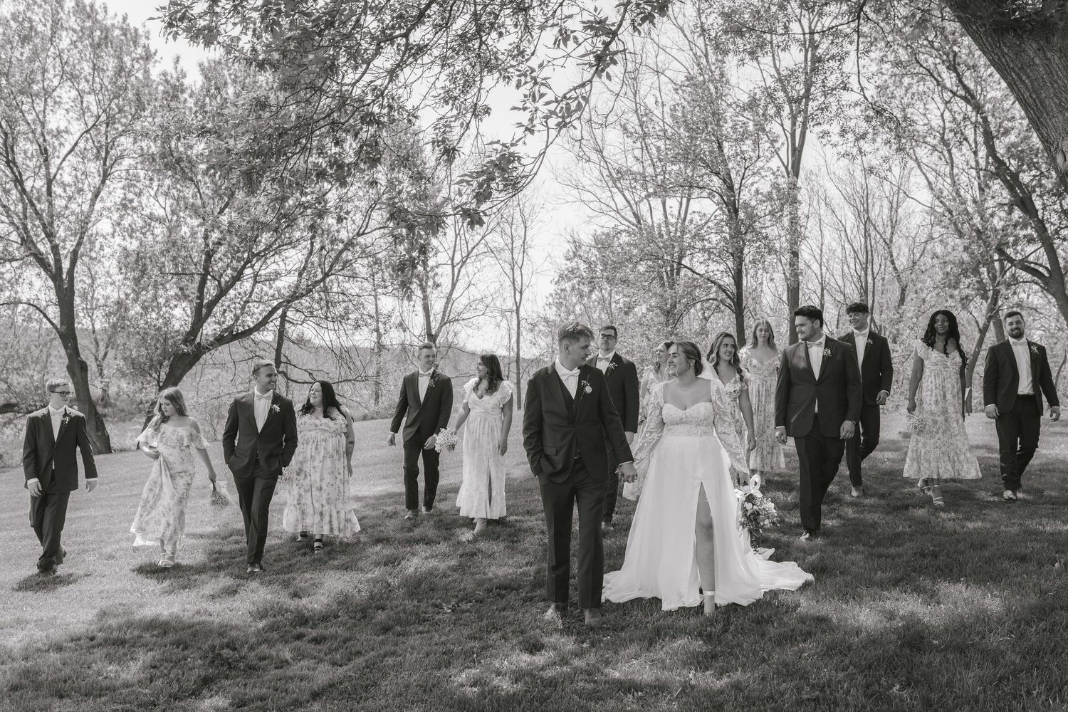 A close-up black and white photo of a bride wearing a delicate lace wedding dress and pearl necklace.