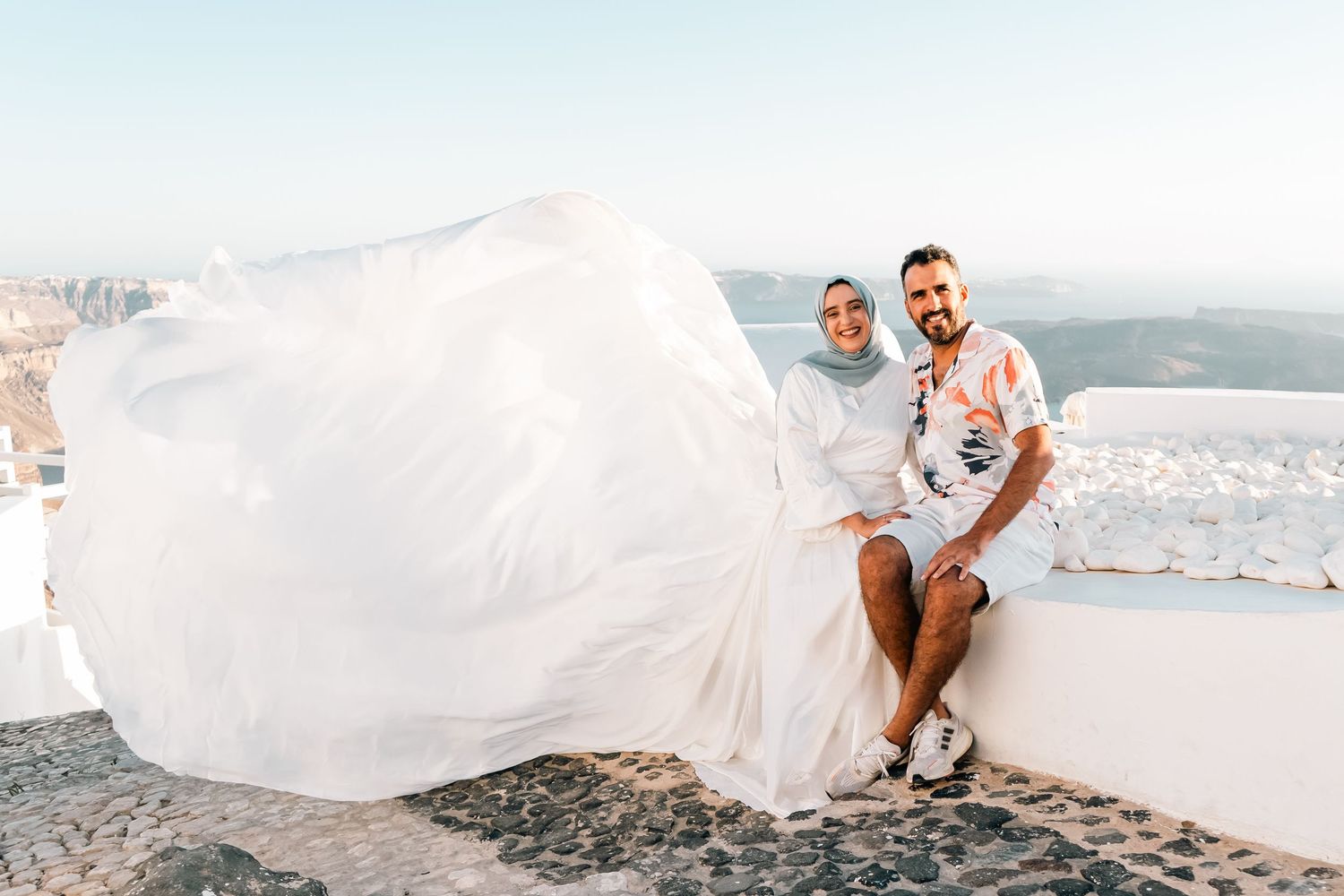 A flowing blue dress creates movement against Santorini's white architecture and sea views.