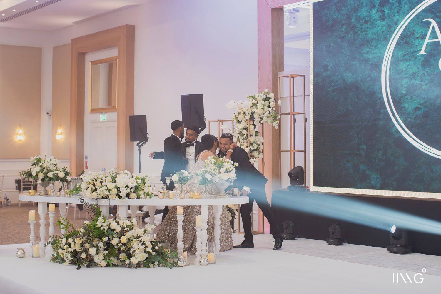 Wedding reception venue with elegant white floral decorations and lighting at a table during an evening celebration.