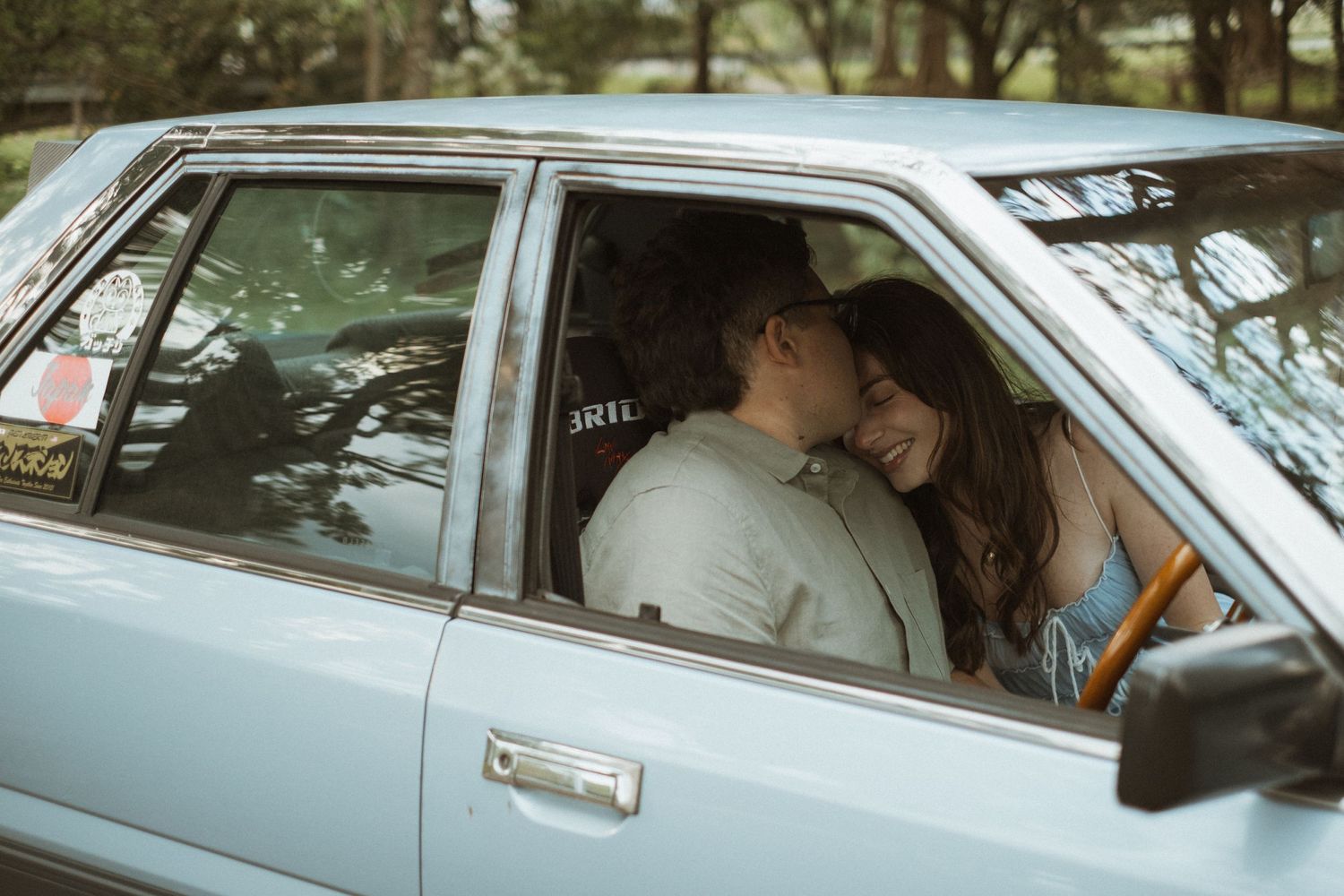 Couple sharing a tender moment inside a classic vintage car.