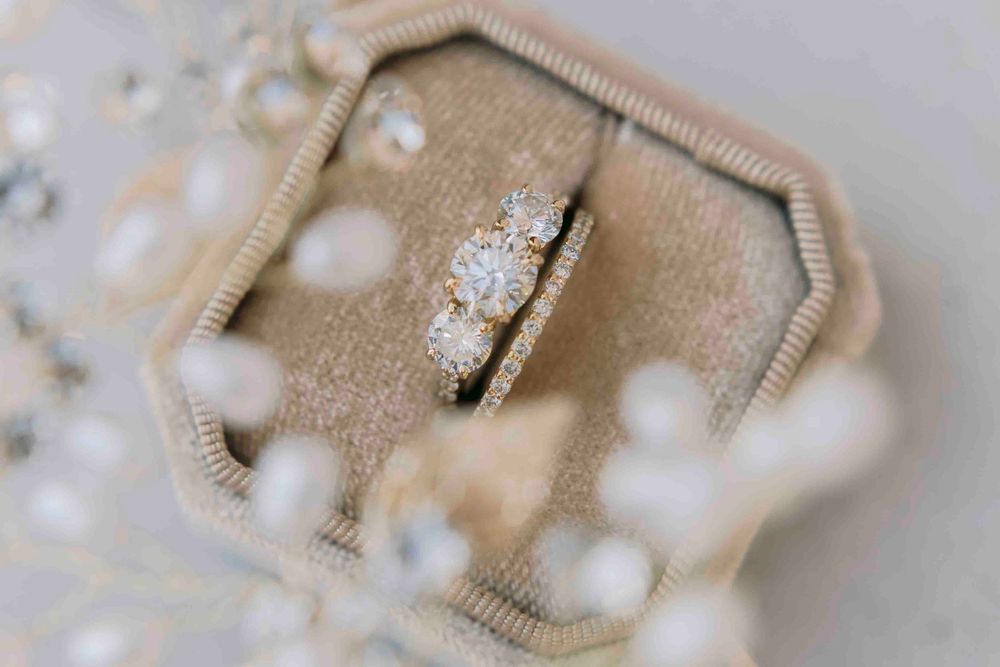 Close-up of a diamond engagement ring and wedding band displayed in a vintage velvet ring box.