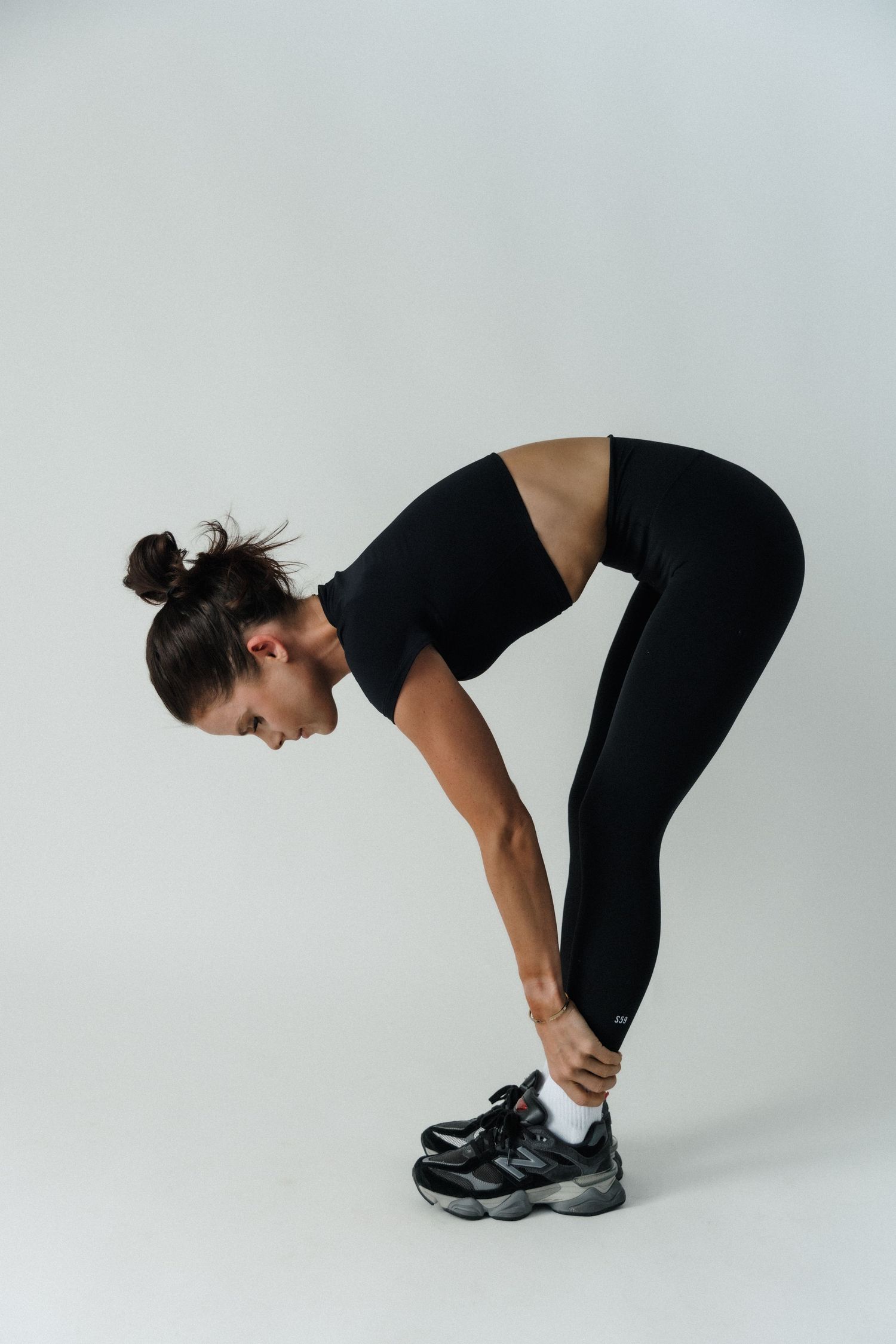 Black and white photo of a woman in athletic wear performing a glute bridge exercise on a studio floor.