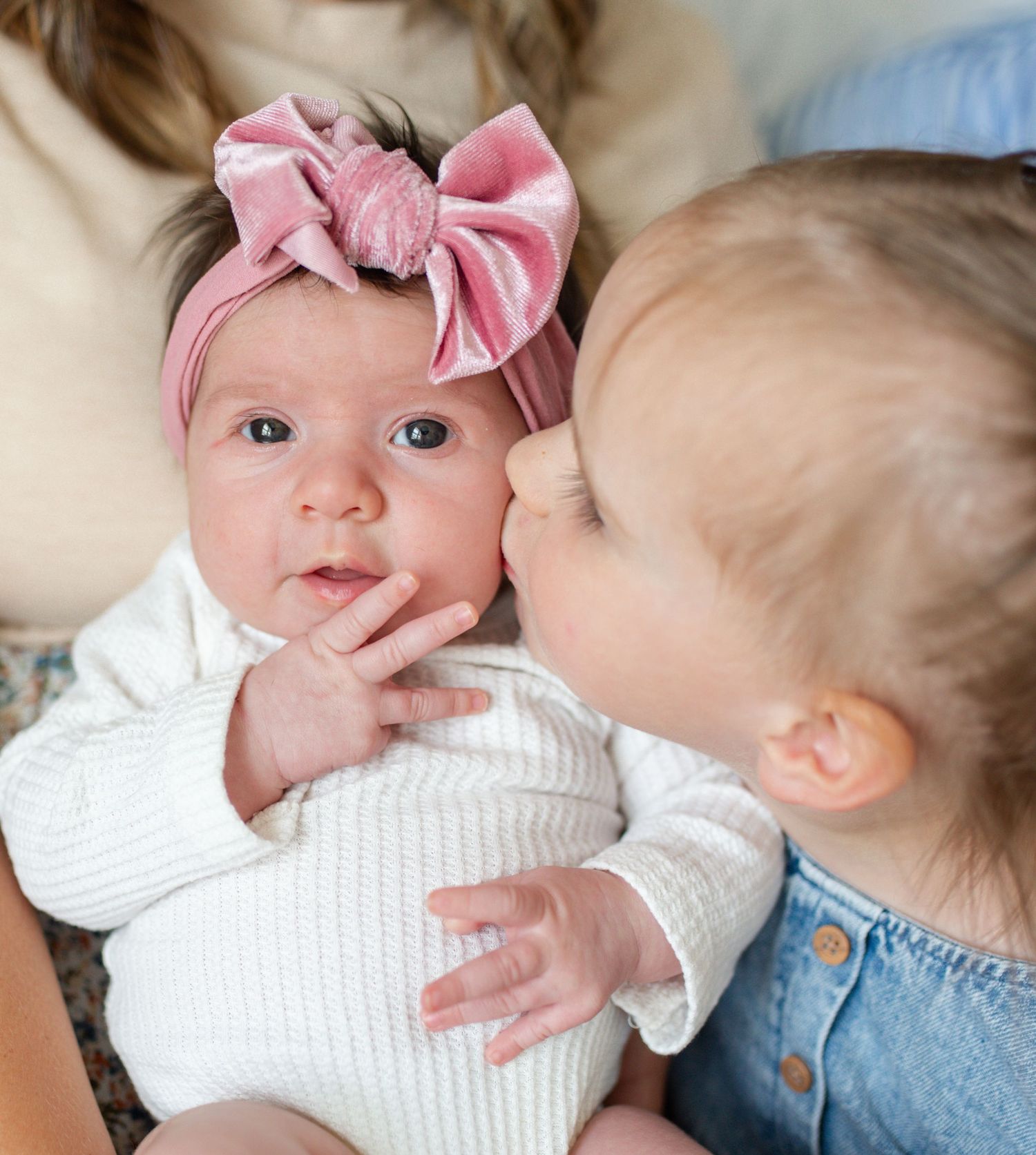 big sister kissing little baby sister during newborn session