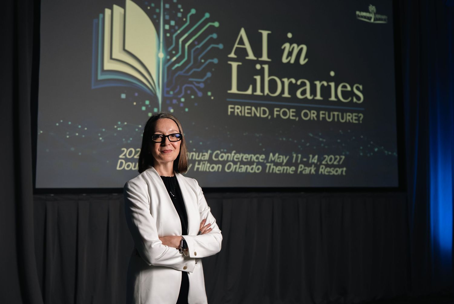 FLA 2026 President, Marina, in white blazer stands before 'AI in Libraries: Friend, Foe, or Future?' conference banner at Hilton Orlando.