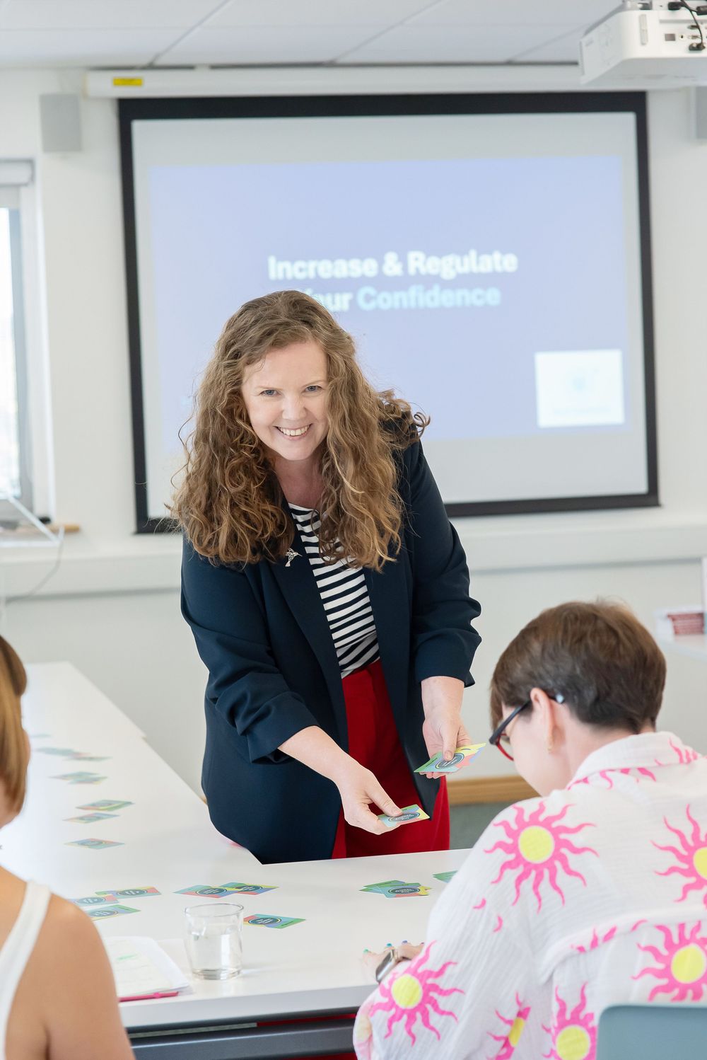 Professional facilitator leads an engaging workshop session with participants at a modern conference table.