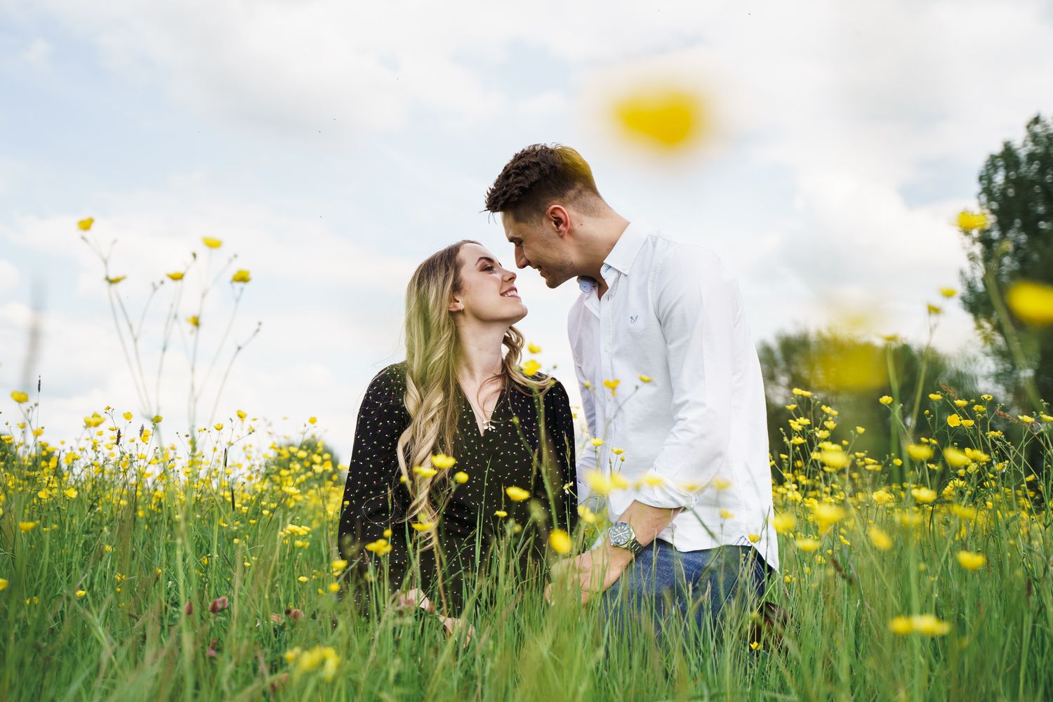 Couple embracing in front of rustic wooden barn doors at a countryside wedding venue under a cloudy sky.