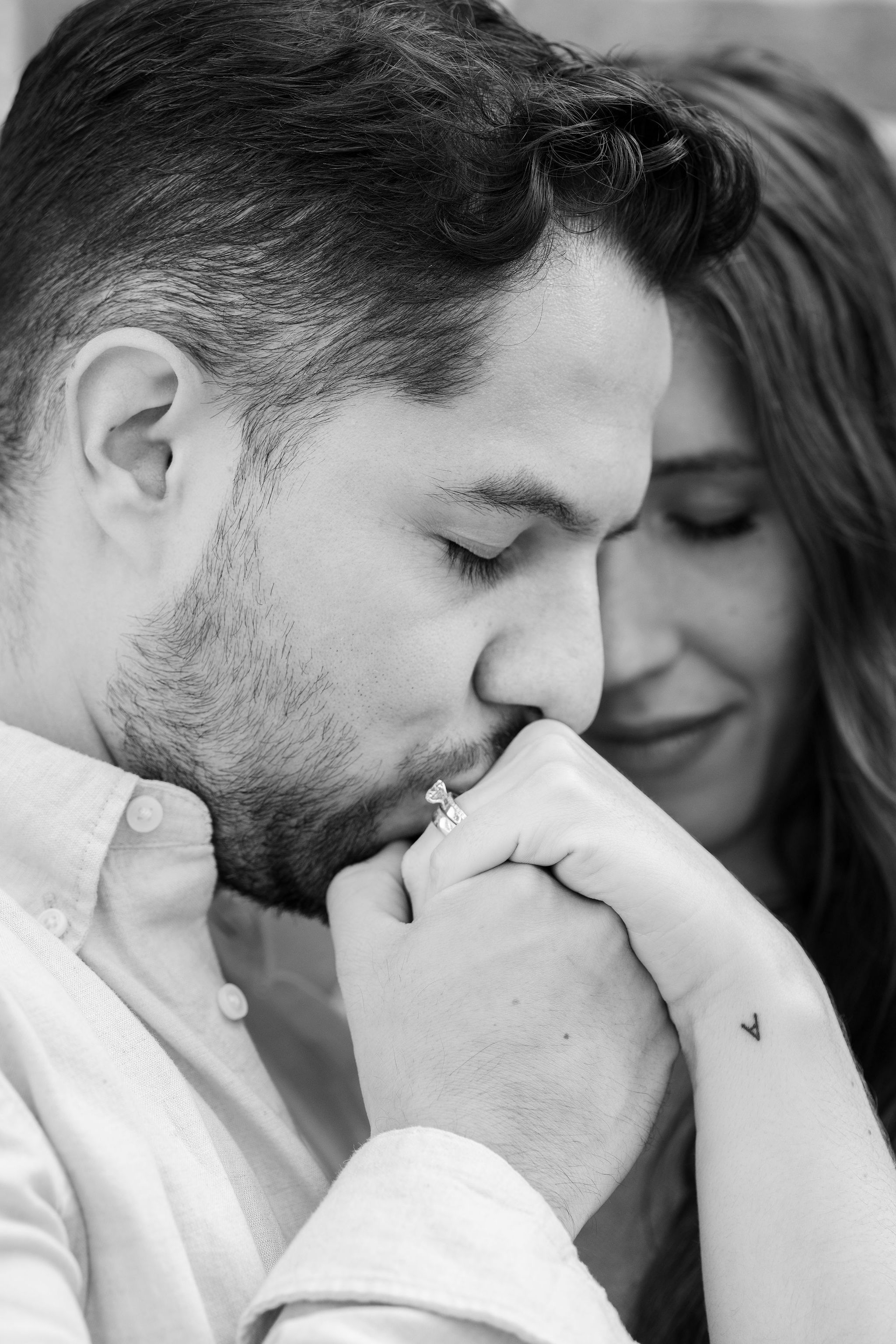 An intimate black and white portrait captures a tender romantic moment between two people.