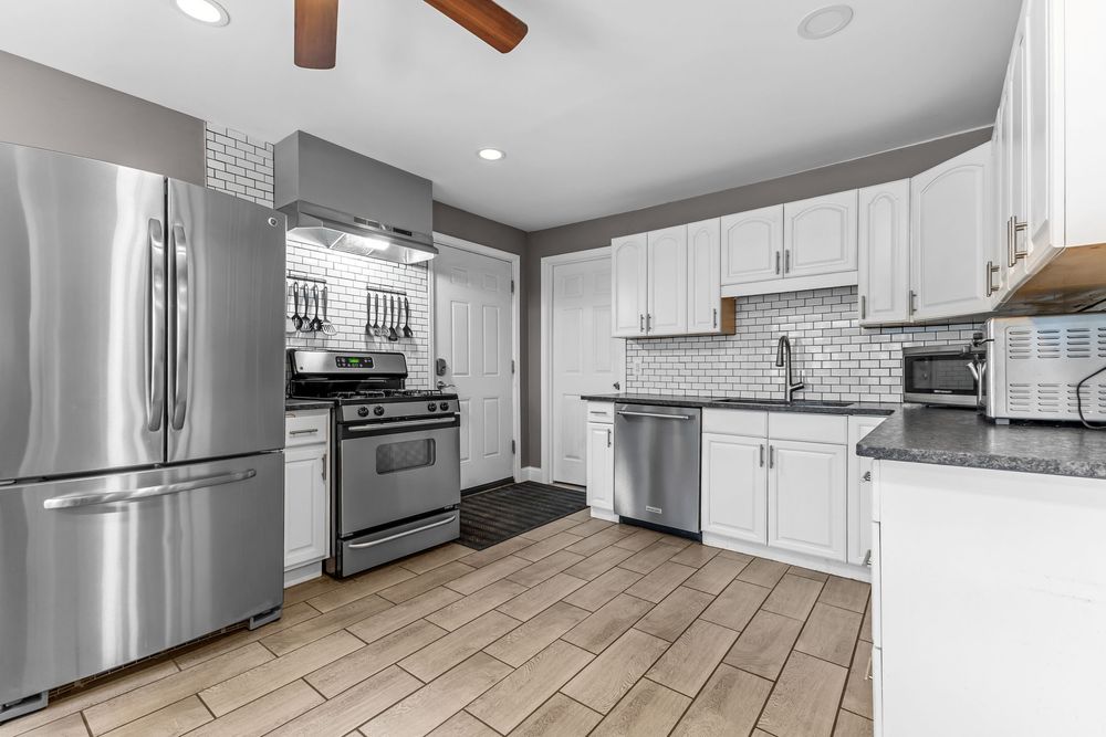 Modern kitchen with stainless steel appliances, white cabinets, subway tile backsplash, and dark countertops.