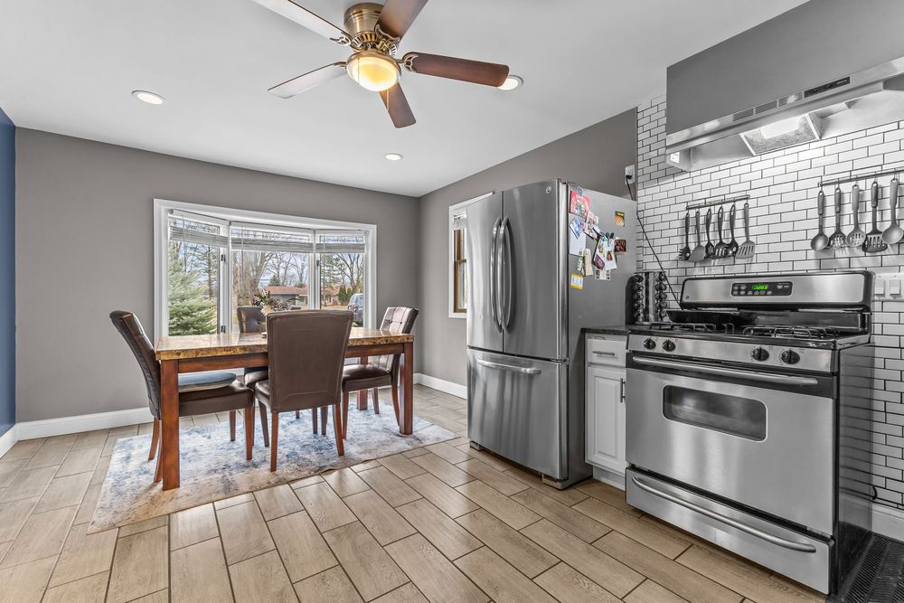 Bright kitchen and dining area with stainless steel appliances, subway tile backsplash, and light wood floors.