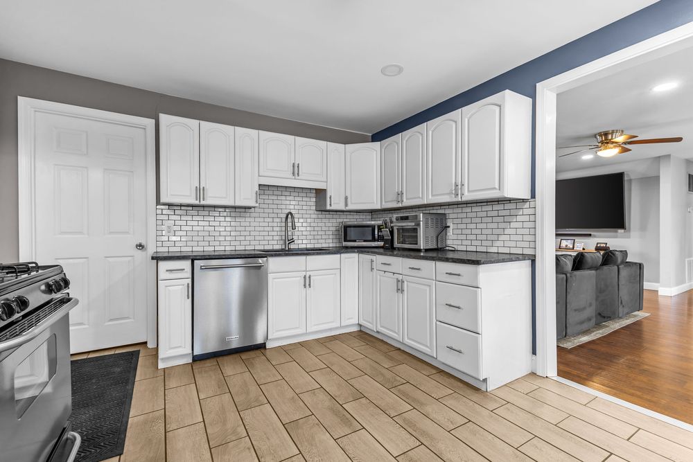 Modern kitchen with white shaker cabinets, subway tile backsplash, and stainless steel appliances.