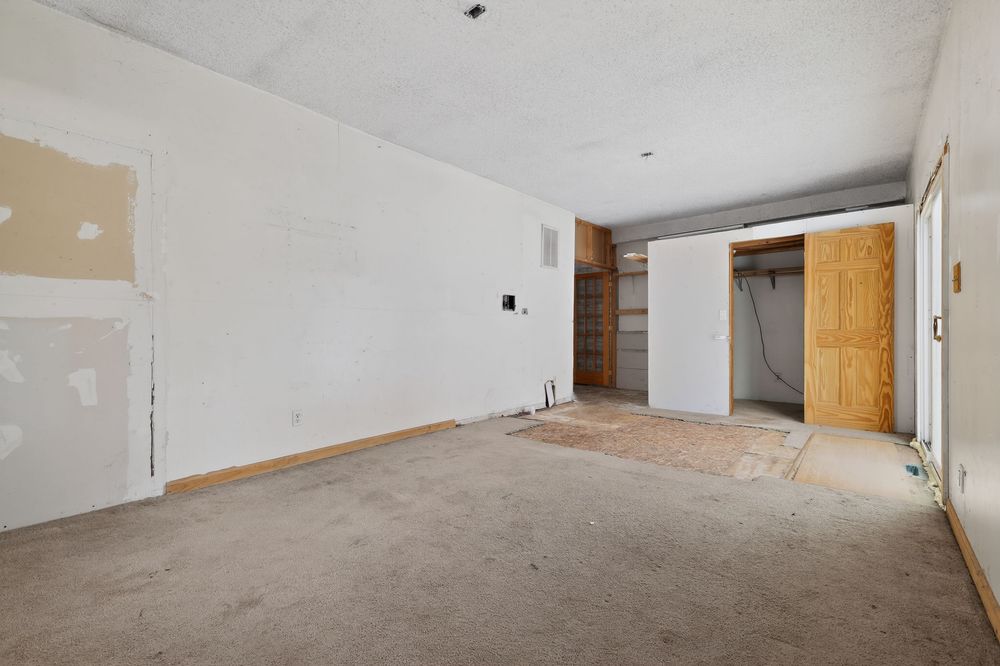 Unfinished room with bare drywall, concrete floors, and a sliding barn door leading to an open storage area.