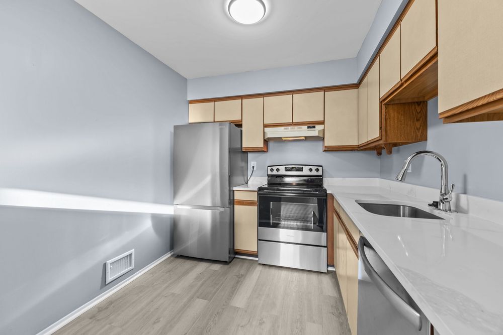 Kitchen with stainless steel appliances, light wood cabinets, and hardwood-style flooring.