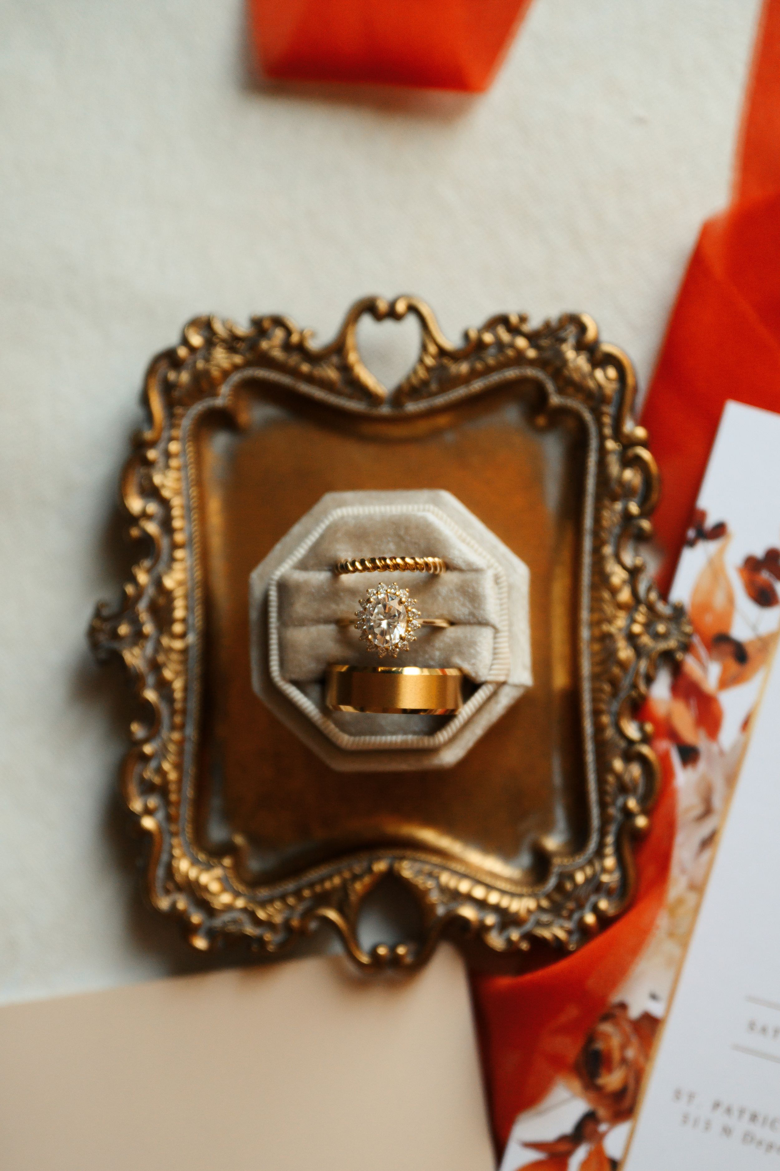 Gold and diamond wedding rings displayed in a velvet ring box on an ornate vintage gold tray.