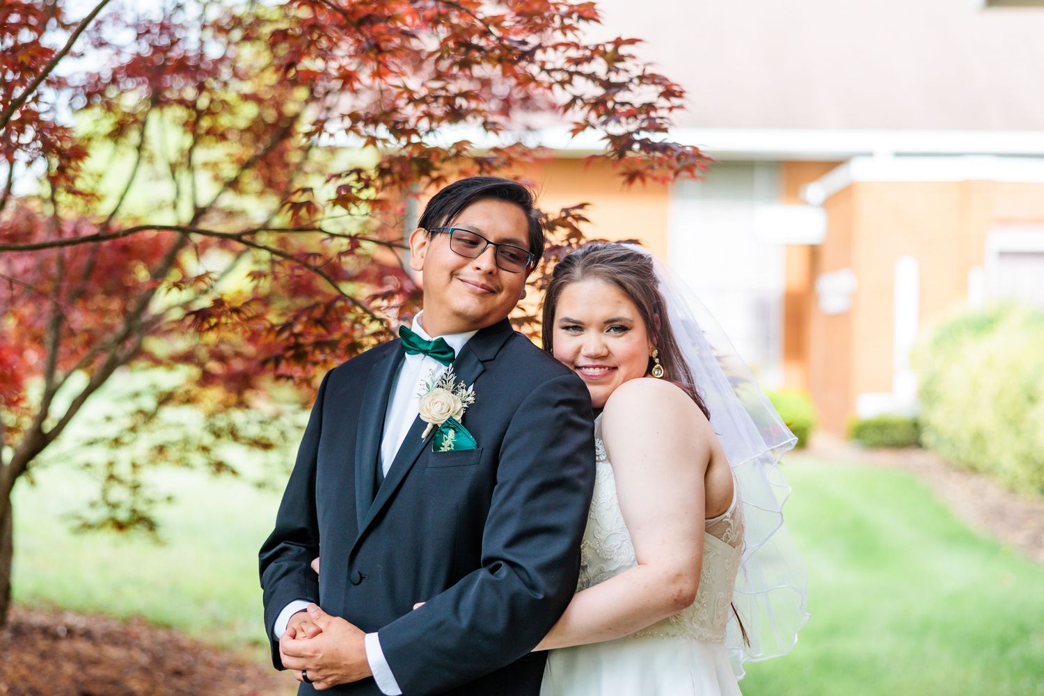 A wedding portrait under a red maple tree featuring elegant formal attire.