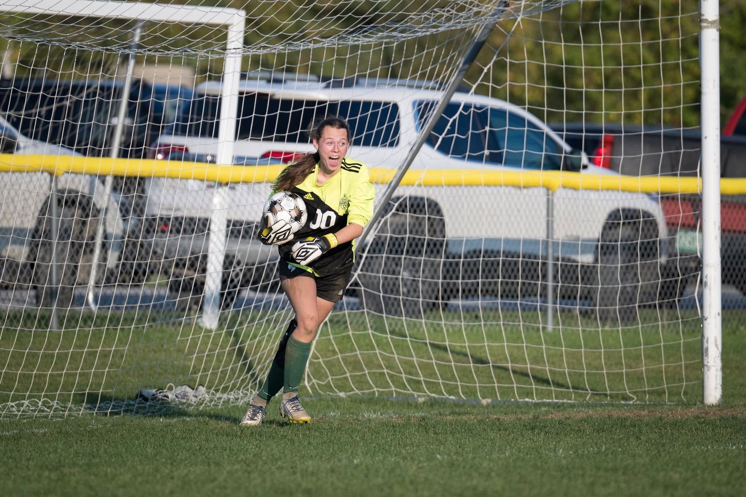Northern Vermont goalkeeper securely holds soccer ball celebrating a save during a Vermont high school soccer game.