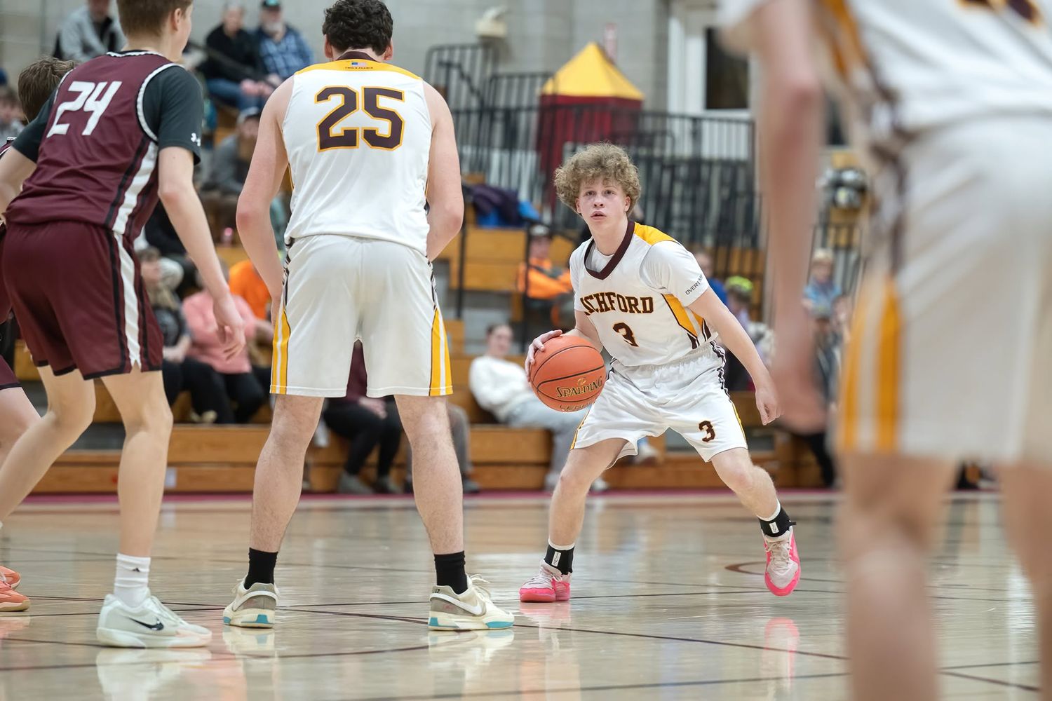 Northern Vermont High school basketball player dribbles ball during an indoor gymnasium game.