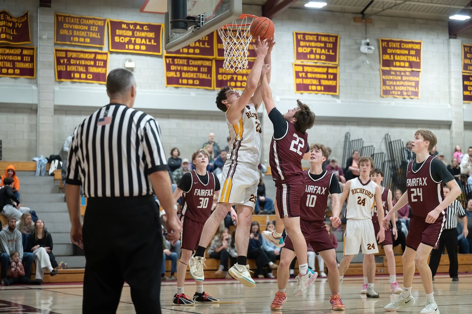 Northern Vermont High school basketball players battle for a layup shot during an intense indoor gymnasium game.
