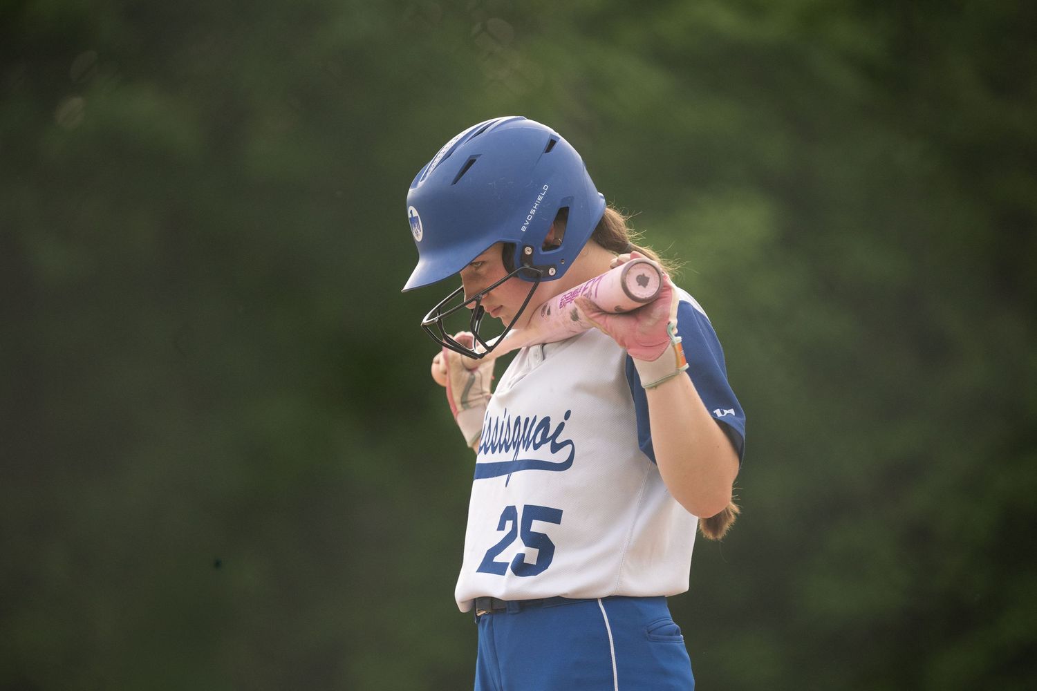 Young softball player in blue helmet and jersey number 25 celebrates during a game.
