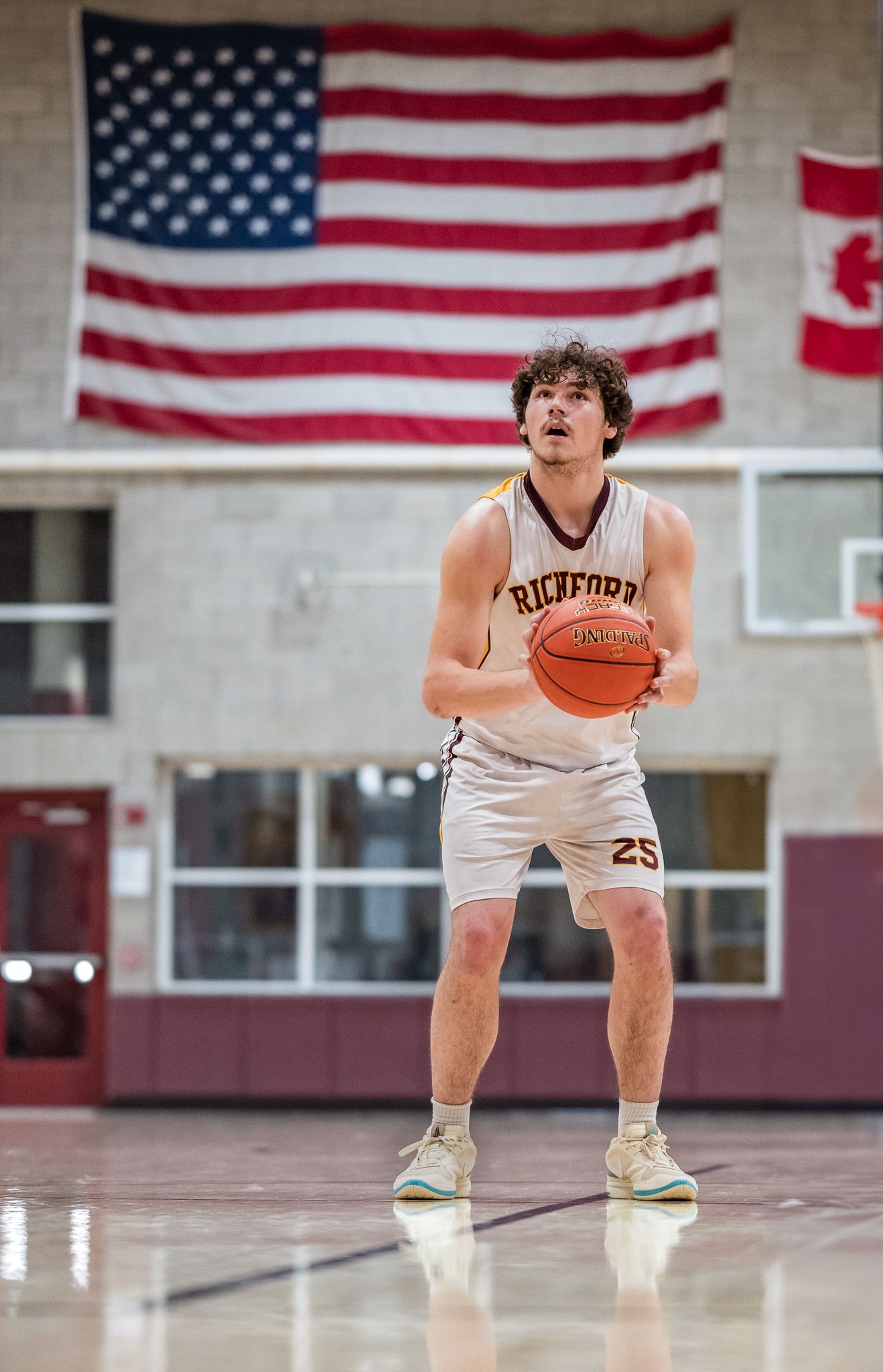 Richford basketball player #25 prepares to shoot free throw in school gymnasium with American flag backdrop.