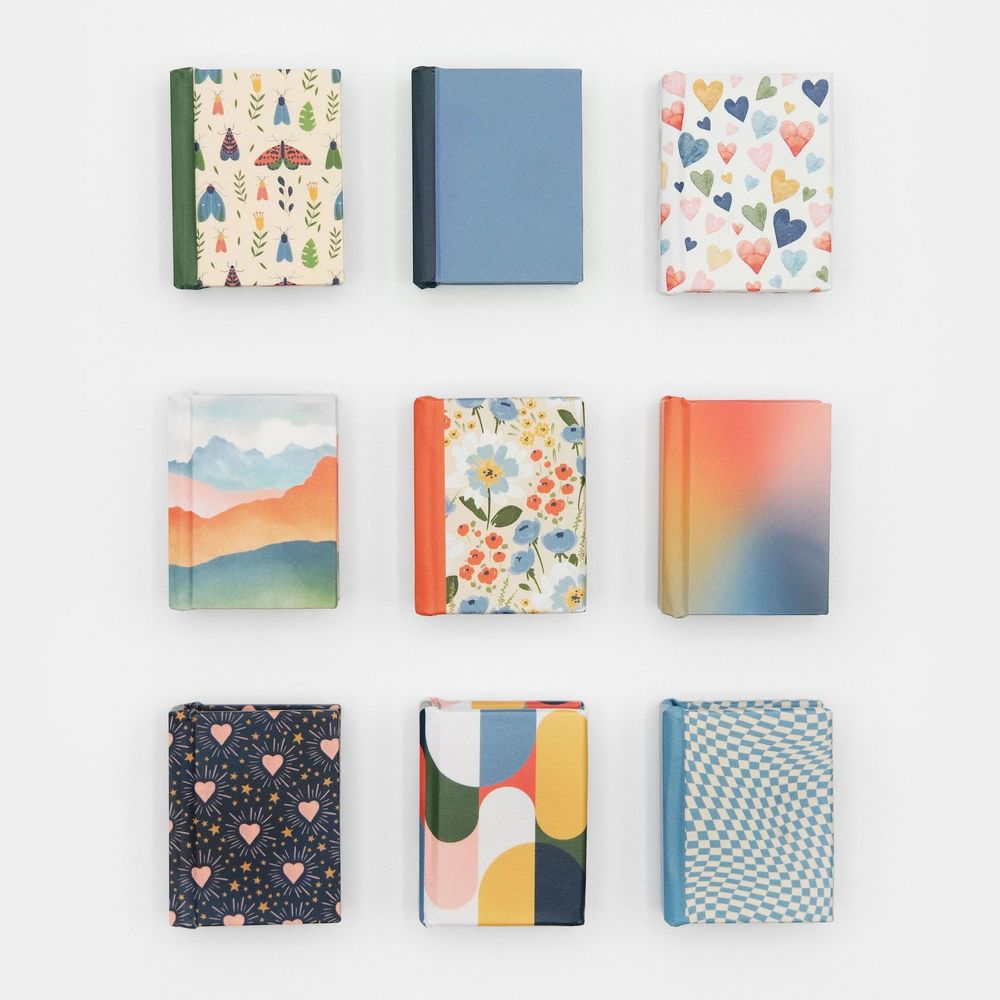 Nine colorful hardcover mini notebooks featuring nature, floral, geometric, and abstract patterns in vibrant hues arranged in a 3x3 grid.
