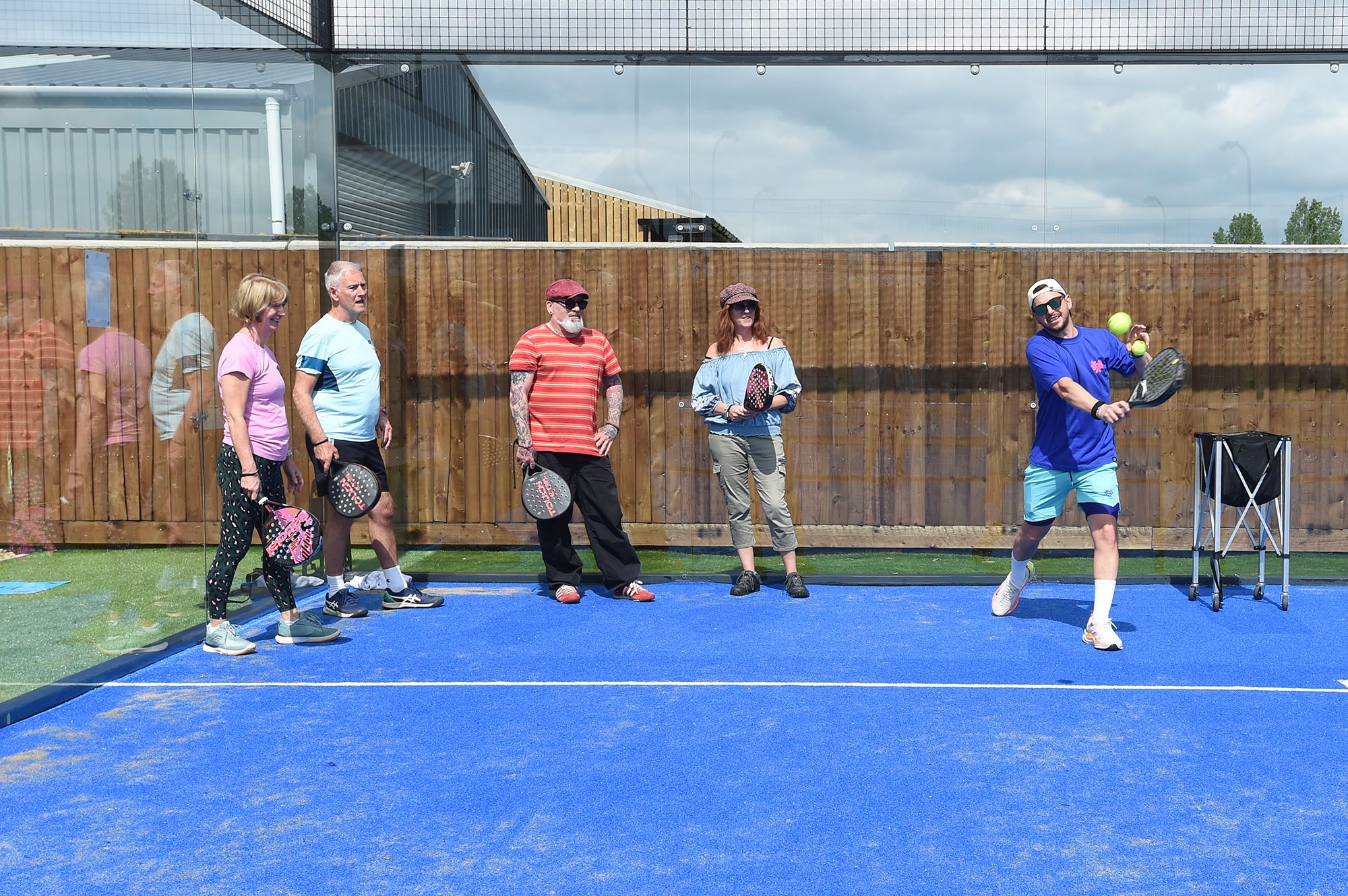 A group of people stands on a tennis court during the Chiltern Padel launch party in Buckinghamshire, captured by Abigail's studio.
