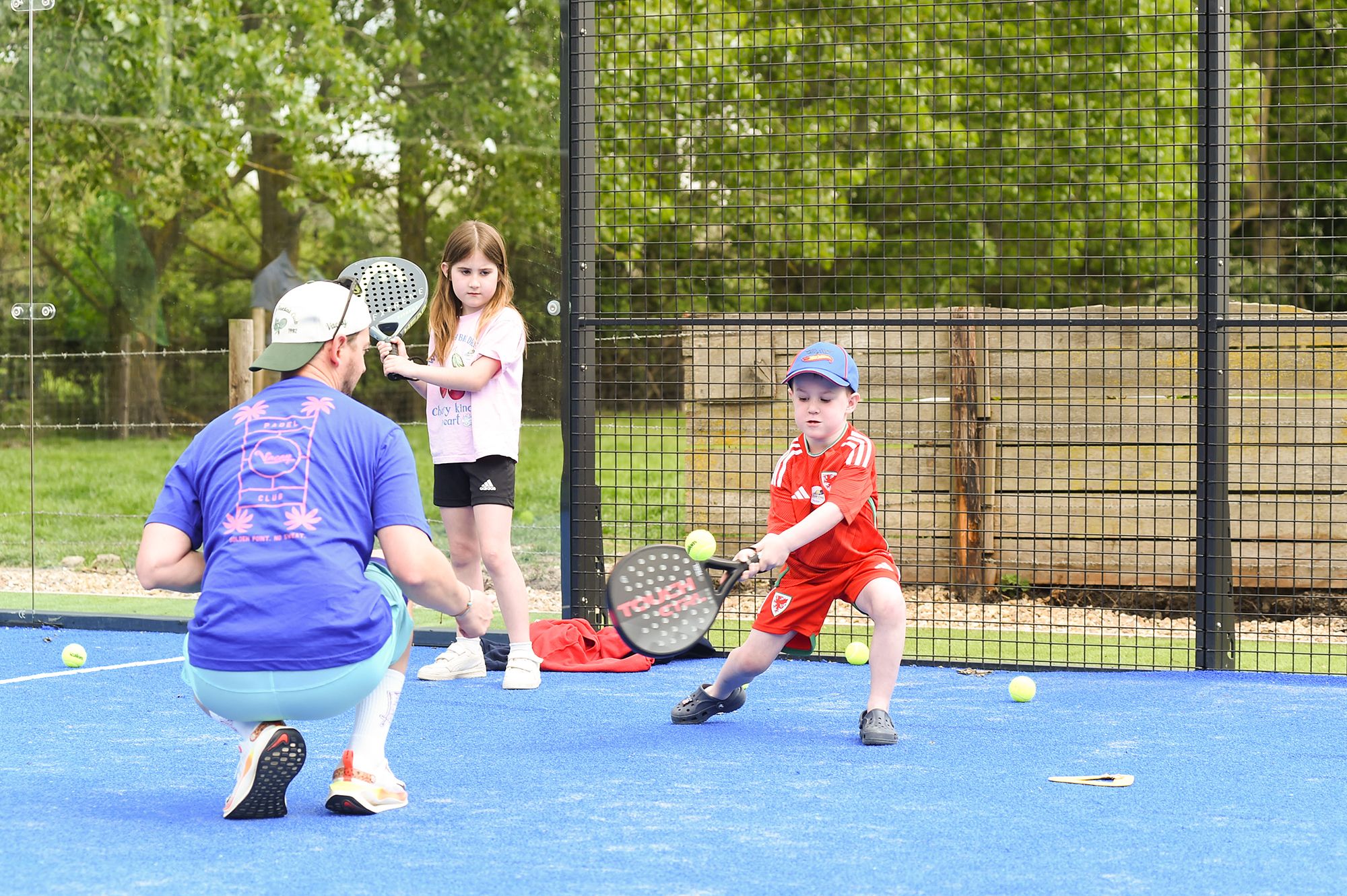 A man and a boy play tennis on a court during the Chiltern Padel launch party in Buckinghamshire, captured by Abigail's studio.