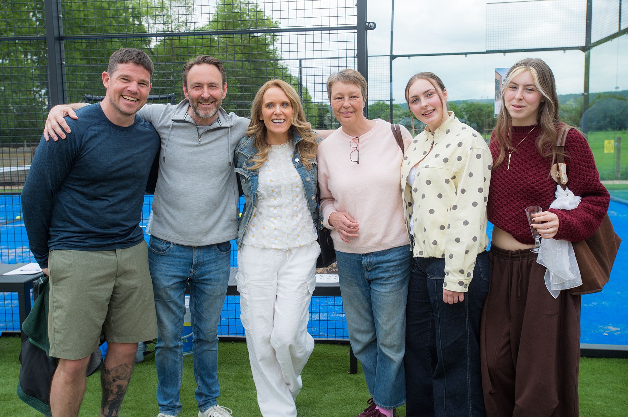 A group of people stands together on a tennis court during the Chiltern Padel launch party in Buckinghamshire.