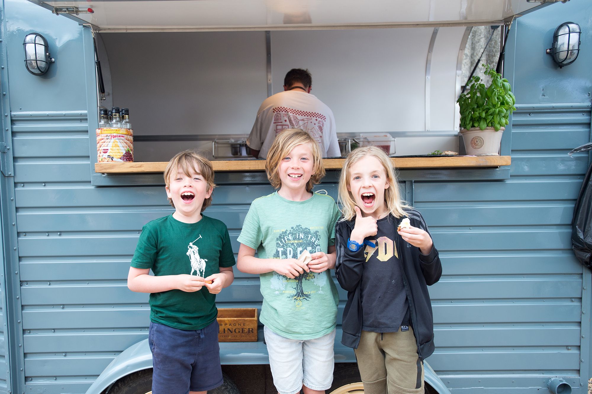 Three children stand in front of a food truck at the Chiltern Padel launch party, photographed by Abigail's studio.