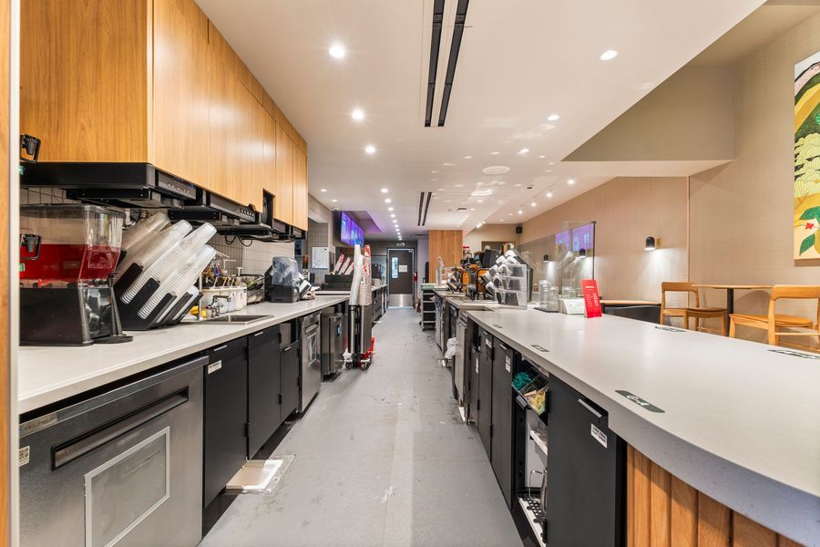 Modern commercial kitchen with long countertops, black cabinetry, and recessed lighting in a sleek open layout.