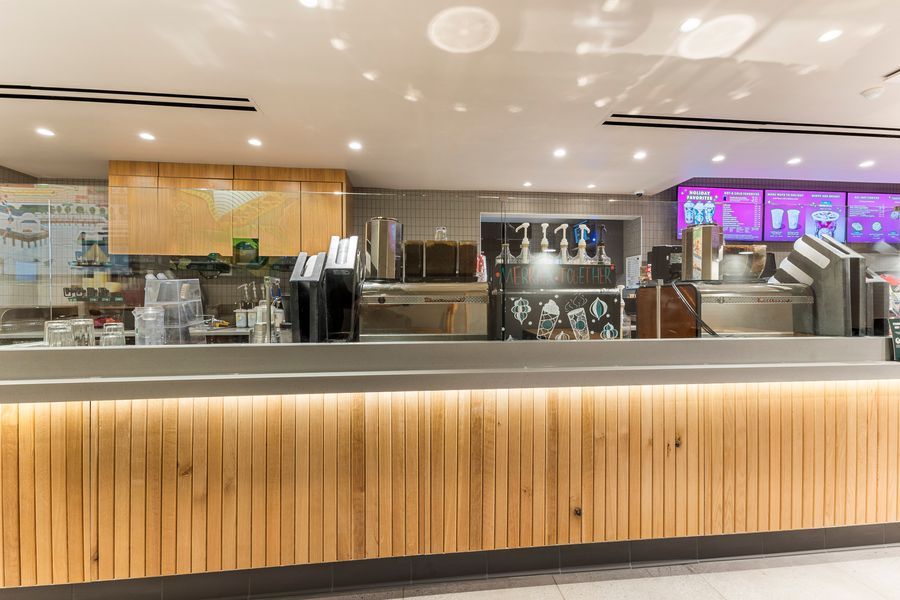 Modern Starbucks coffee bar counter with warm wood paneling and professional espresso equipment.