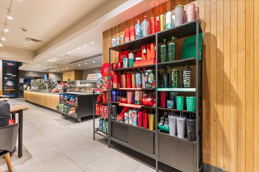 Starbucks retail display shelf with colorful tumblers and merchandise inside a modern store location.