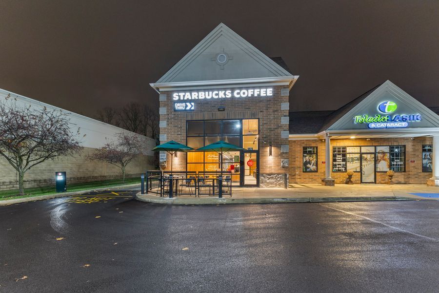 Starbucks Coffee drive-thru location exterior at night with illuminated signage in parking lot.