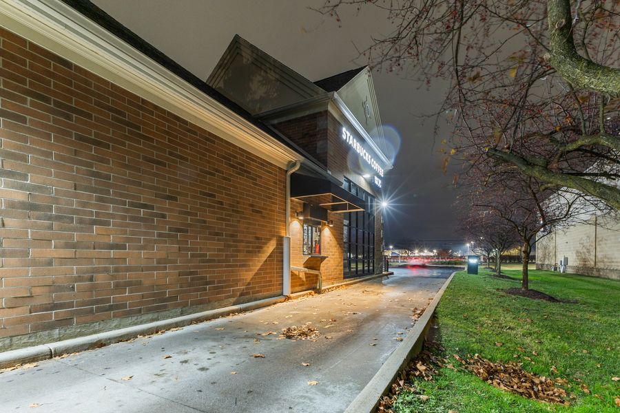 Exterior brick building entrance at night with pathway lighting and foggy autumn surroundings.