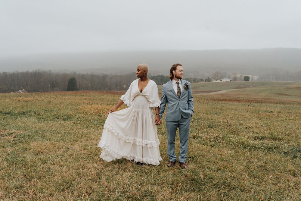 Bride and groom holding hands in a misty field at Boyd Big Tree Preserve in Harrisburg, PA bride in flowing white gown, groom in gray suit.
