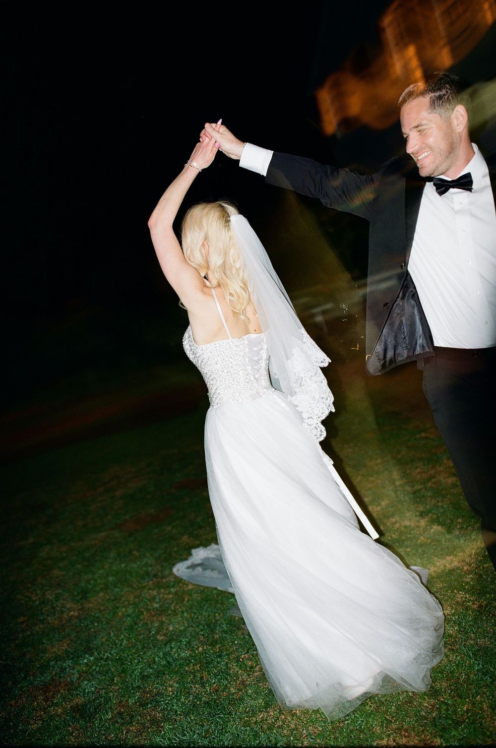 Groom spins bride in candid fun dance caught on film photography with direct flash
