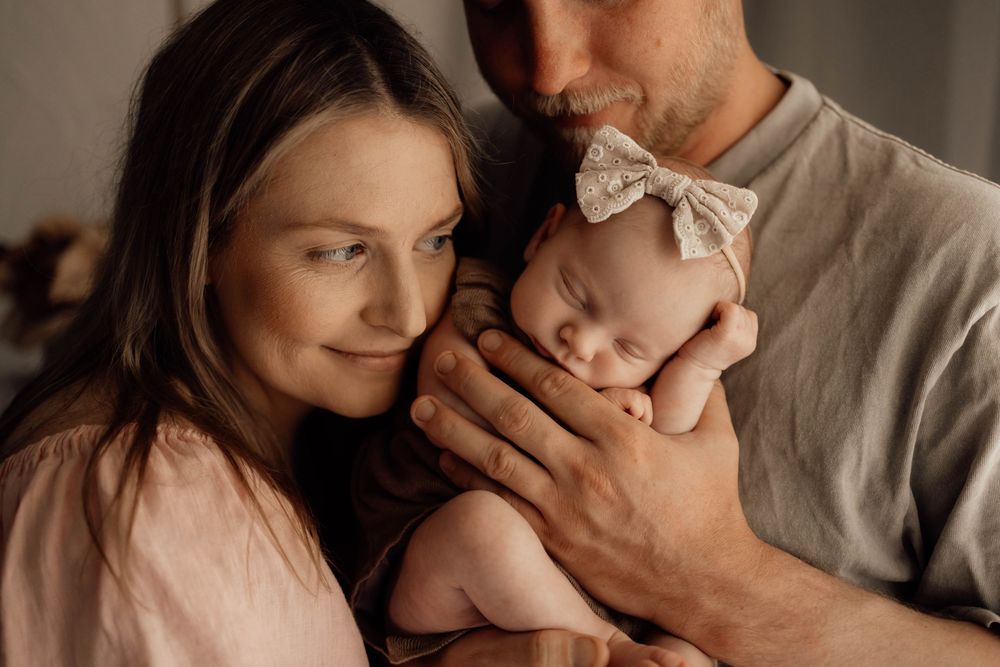 Parents tenderly holding their sleeping newborn baby, captured in a warm and intimate family portrait photography session.