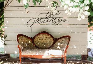 Vintage floral loveseat in front of white shiplap wall with elegant cursive The Pettigreys wedding sign.