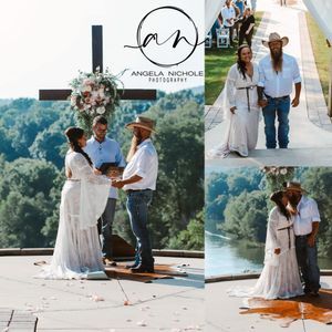 Outdoor wedding ceremony with couple exchanging vows at floral cross, bride in lace gown, scenic river backdrop.