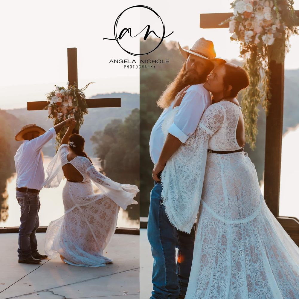 Outdoor wedding ceremony with bride in lace gown and groom in cowboy hat, exchanging vows near a wooden cross at sunset.