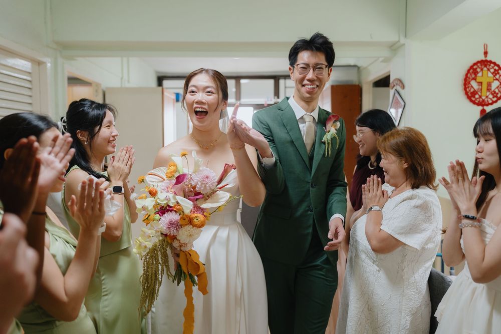 Joyful bride and groom walk through cheering guests in a wedding ceremony, bride holding a colorful bouquet.