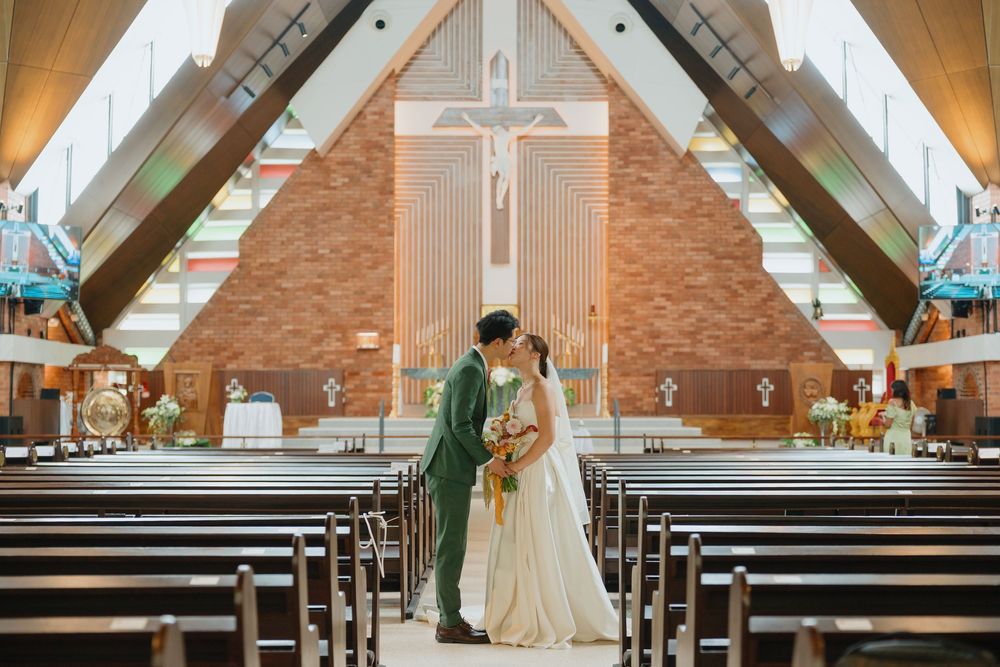 Bride and groom share a kiss in a beautiful church aisle on their wedding day.