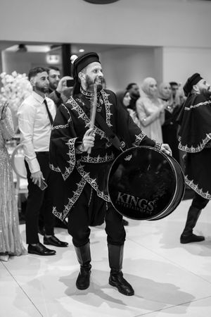 Dancers in ornate black and white embroidered costumes performing at an indoor event.