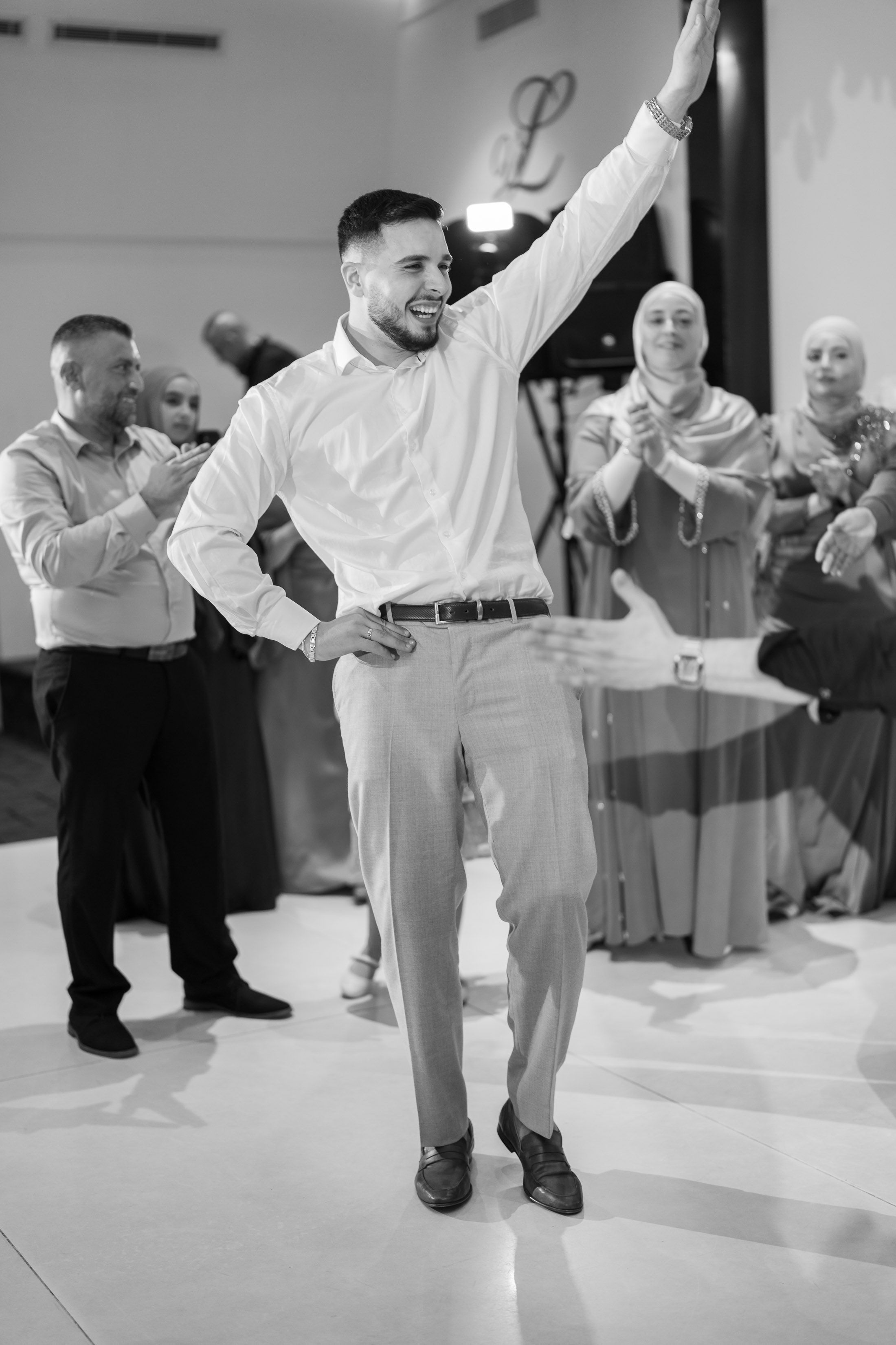 Dynamic black and white photo of wedding guests dancing and celebrating on the dance floor.