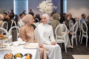 Modern wedding reception venue with white chairs and elegant table settings.