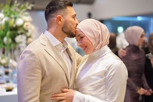 Couple sharing a romantic moment at their wedding reception in elegant formal attire.