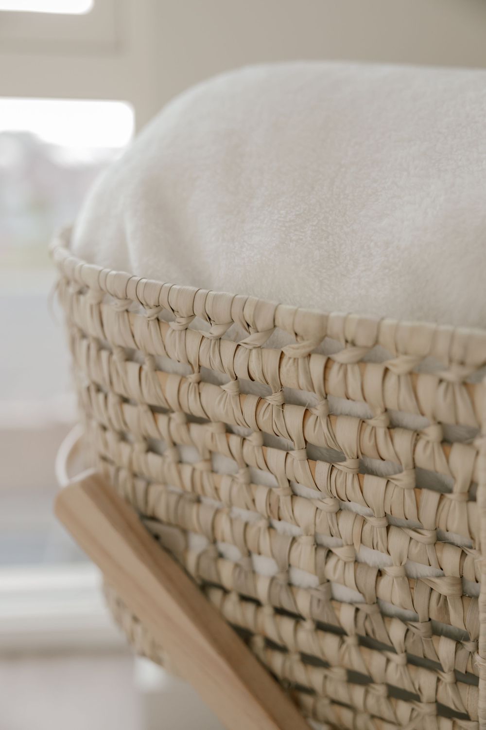 Close-up view of a woven natural rattan basket with white cushioning on top showing intricate weave pattern detail.